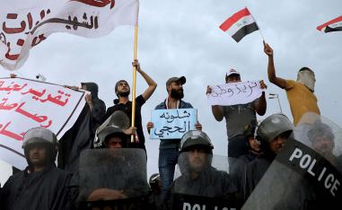 raqi policemen stand in front of demonstrators during a protest over corruption, lack of jobs, and poor services, in Kerbala