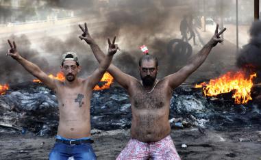 Lebanese demonstrators gesture as tires burn behind them