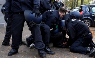 Police officers detain a man as Kurds demonstrate against Turkey's military action in northeastern Syria in Berlin