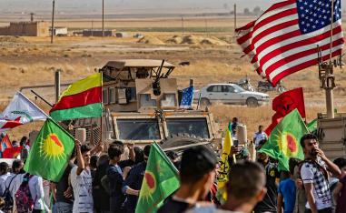 Syrian Kurds gather around a US armoured vehicle during a demonstration against Turkish threats next to a base for the US-led international coalition on the outskirts of Ras al-Ain town in Syria's Hasakeh province 