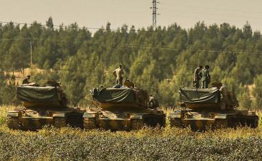 Turkish soldiers stand atop of their tanks at a staging area close to the border with Syria in Sanliurfa province, southeastern Turkey