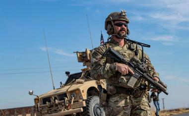 A US soldier stands by an armoured vehicle during a patrol of the northern countryside of the northeastern Syrian town of al-Malikiyah 