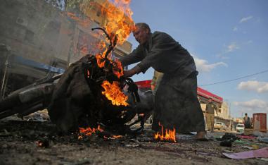 A Syrian man stands next to a burning motorcycle at the site of a car bomb explosion in the northern Syrian Kurdish town of Tel Abyad