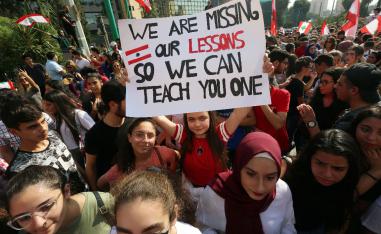 A student carries a banner during ongoing anti-government protests near the Ministry of Education and Higher Education in Beirut