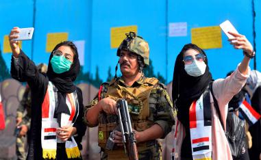 Iraqi students pose for selfies with a member of the security forces during ongoing anti-government protests in Diwaniyah