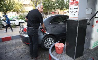 A man fills up his car's tank at a petrol station, after fuel price increased, in Tehran