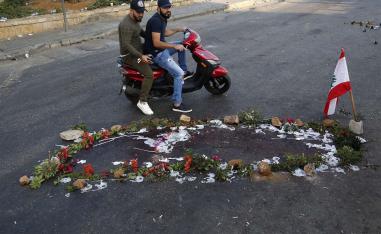 Lebanese people pass by the scene where a local official for a Lebanese political party was shot dead by a Lebanese soldier, in Khaldeh