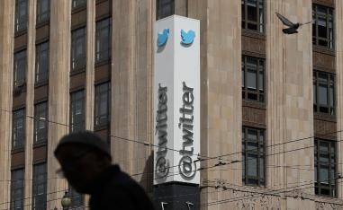 A pedestrian walks across the street from the Twitter office building in San Francisco