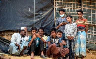 Rohingya refugees watch on a mobile phone a live feed of Myanmar's State Counselor Aung San Suu Kyi's appearance at the UN's International Court of Justice in the Hague