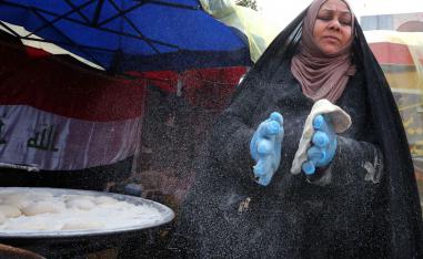 An Iraqi woman prepares traditional bread on the sidelines of ongoing anti-government protests at Tahrir square