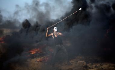 A Palestinian protester hurls stones at Israeli troops during a protest in Gaza