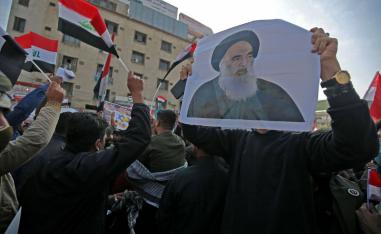 Protesters carry a picture of Shiite cleric Ali al-Sistani