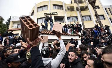 Algerian demonstrators carry bricks to build a wall at the entrance of the daira (sub-prefecture) of Tizi-Ouzou