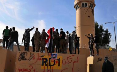 Pro-Iranian militiamen and their supporters look into the US embassy compound in Baghdad