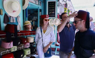 A tourist tries on a Tunisian “chechia” (traditional fez) in a shop at a bazaar in the Medina (old town) of Tunis