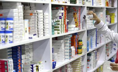 A drugstore employee reaches for medicine from shelf in Tehran