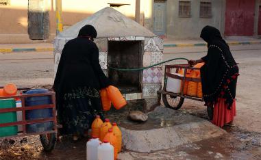 Moroccan women filling up containers with water from a hose in Zagora