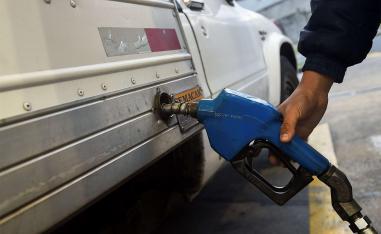 A worker refuels a truck at a gas station