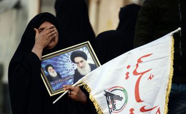 A mourner for Soleimani and Muhandis carries a framed image of Iraq's Grand Ayatollah Ali Sistani