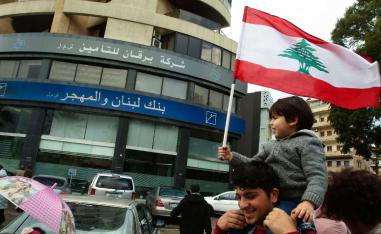 A Lebanese protester carries a child as he takes part in a rally in front of a bank in the southern city of Sidon (Saida) on December 30, 2019
