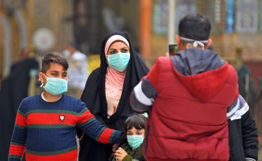 Iraqis wearing masks walk on February 25, 2020 in the partially deserted streets of Iraq's central shrine city of Najaf