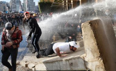 Anti-government protesters are sprayed with a water cannon during a protest, in downtown Beirut