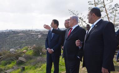Israeli PM Benjamin Netanyahu (2-R) points from an overview at the Israeli settlement of Har Homa 