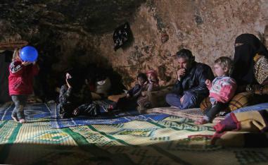 Darra's children huddle on a carpet around a tray covered in small bowls of hummus and dried oregano