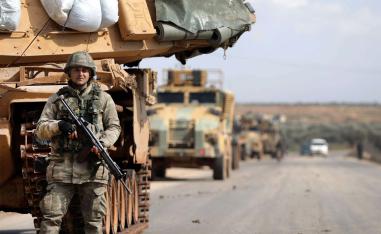 Turkish soldier stands in front of a military vehicles convoy east of Idlib city in northwestern Syria 
