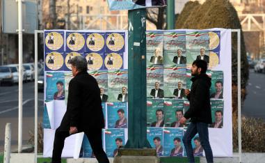 Iranians walk past electoral poster in a street of the capital Tehran