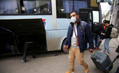 A man wearing a protective face mask walks with luggage, following the outbreak of coronavirus disease in Algiers