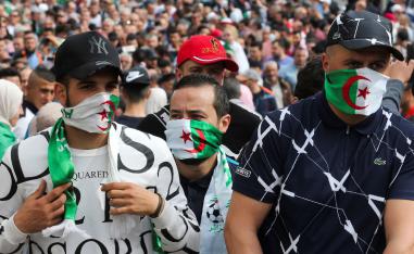 Demonstrators cover their faces with national flags during an anti-government protest in Algiers