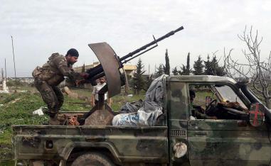 Syrian army soldiers gesture from a military vehicle in southern Idlib province