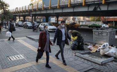 Iranians woman wear face protective masks as they walk on a street in the Tehran business district