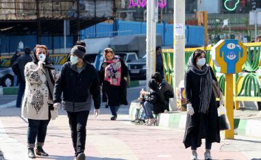 Iranian pedestrians walk while wearing protective masks in Tehran