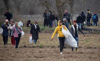 Migrants walk on the field near the Turkey's Pazarkule border crossing with Greece's Kastanies