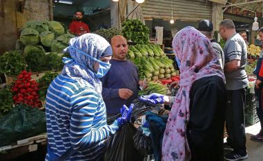 Women buy fresh vegetables at a market in Amman