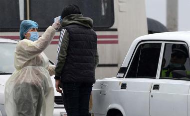 A medical worker in protective suit checks the body temperature of a person at a checkpoint in the city of Vagharshapat