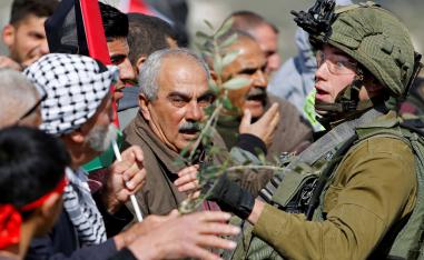 Palestinian demonstrators confront an Israeli soldier during a protest against Israeli settlements