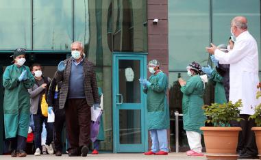 Medical staff members applaud patients who have recovered from COVID-19