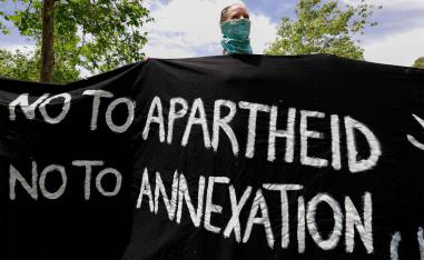 Israeli activist holds a banner during a protest against the US peace plan for the Middle East, in front of the US ambassador's residence in Jerusalem