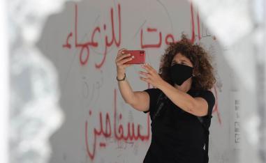 المخرجة اللبنانية كارول منصور في سيلفي مع شعارات على الحائط في بيروت