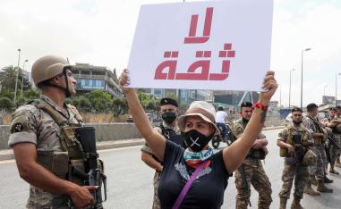 A Lebanese anti-government protester holds a placard reading "No Trust" in front of army soldiers as she takes part in a demonstration near the presidential palace in Beirut