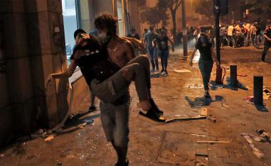 A Lebanese protester carries a wounded demonstrators to safety at the headquarters of the Lebanese association of banks 
