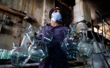 عامل يغسل أباريق في مصنع بطرابلس يقوم بإعادة تدوير الزجاج المكسور نتيجة انفجار بيروت 
