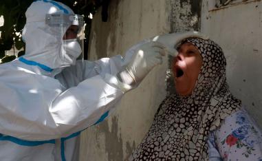 عضو في لجنة التقصي الوبائي يأخذ مسحة من مواطنة في عمان