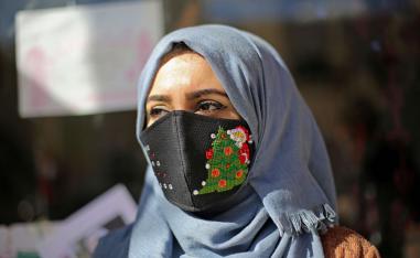 امرأة فلسطينية ترتدي كمامة برسم لرمز لعيد الميلاد في مدينة غزة 