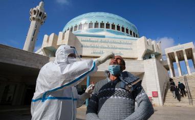 عضو في فريق التقصي الوبائي يأخذ مسحة أنف عشوائية من رجل يغادر مسجدا في وسط العاصمة عمان