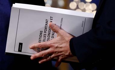 French President Emmanuel Macron holds the report on the memory of the colonisation and the Algerian war