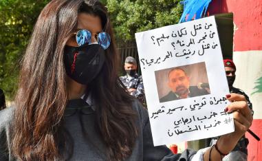 متظاهرة لبنانية ترفع صورة لقمان سليم وتتهم حزب الله بقتله